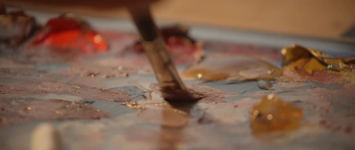 A paintbrush mixes paint on a palette