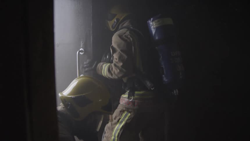 Firefighters search in a dark building