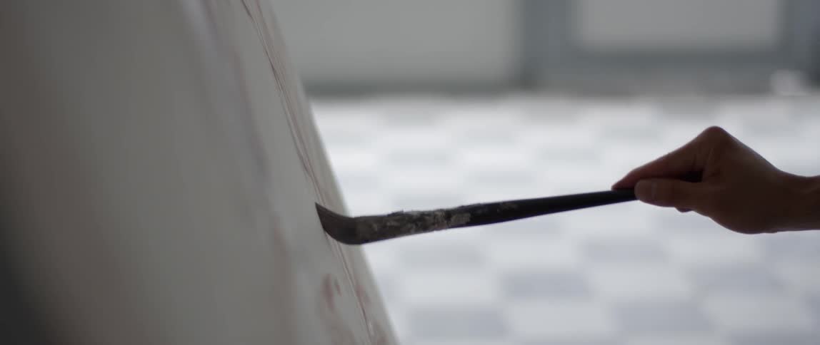 Person uses a paintbrush to paint lines on a canvas