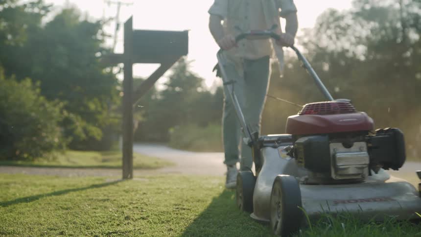 A man mows a lawn on a sunny day
