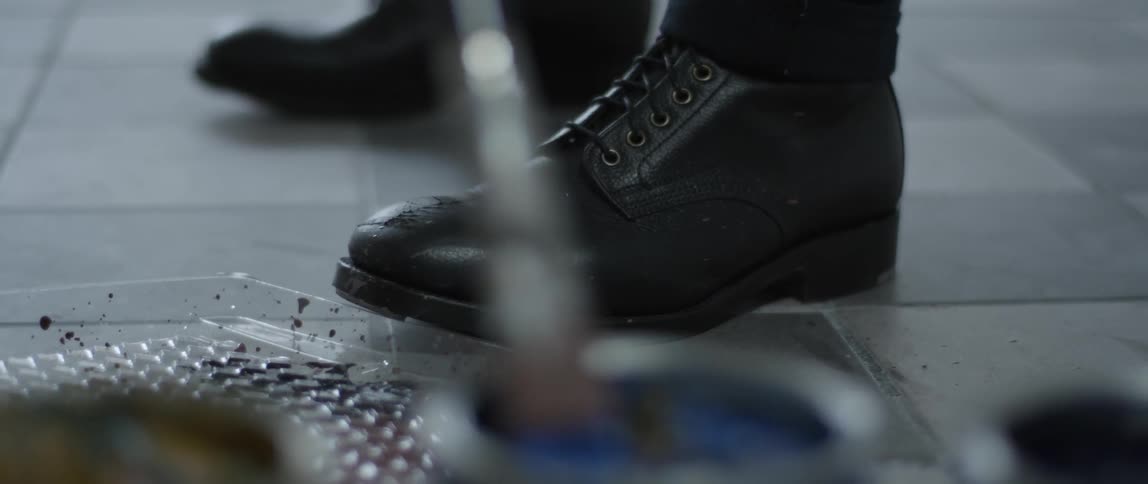 A man mixes paint in a palette on the floor