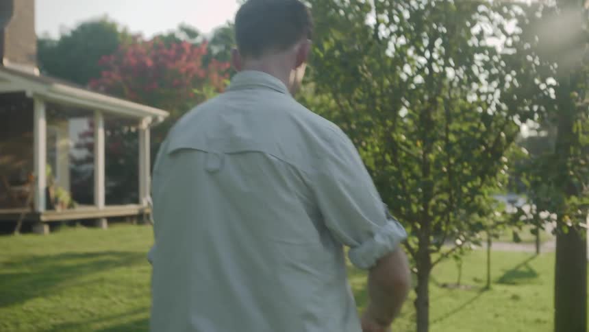 Man Steers Mower Around Base of Tree