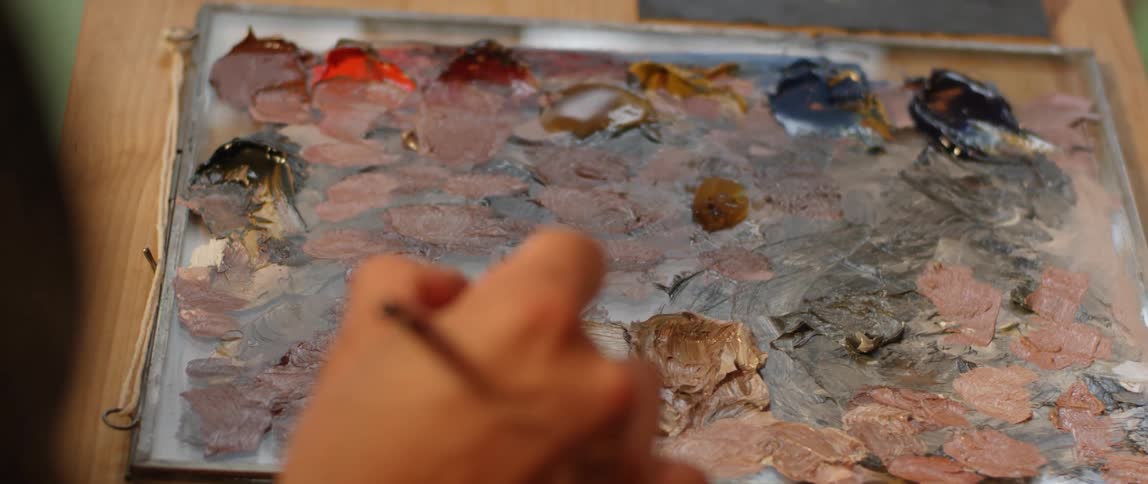An artist mixes paint on a palette