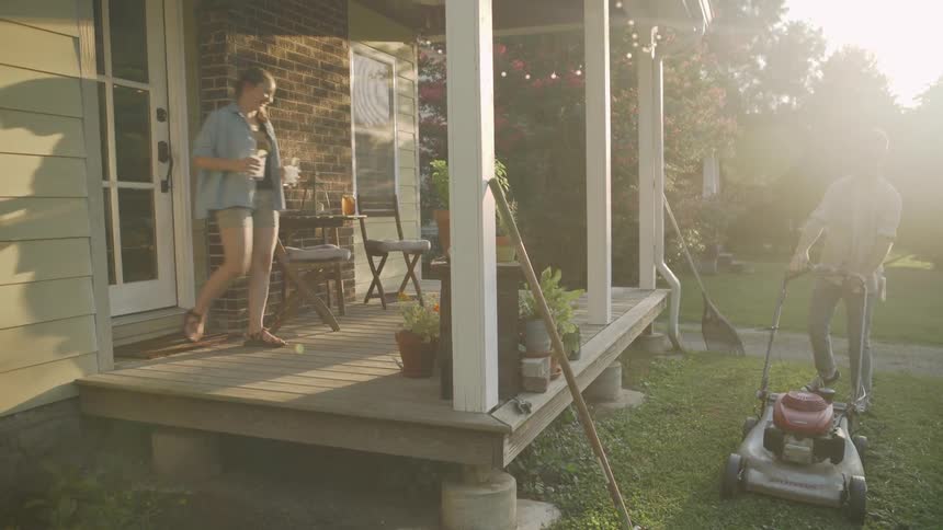 Woman leaves the house and goes on the porch as a man joins her after mowing the grass