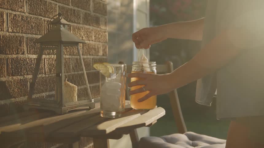 Hands Remove Tea Bags from Jar of Sun Tea