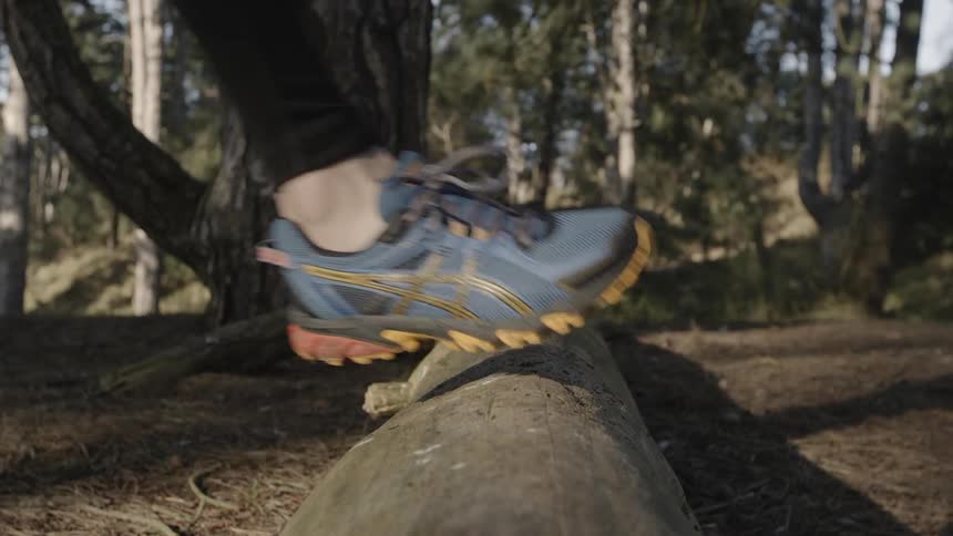 A person jumps over a fallen tree in the woods