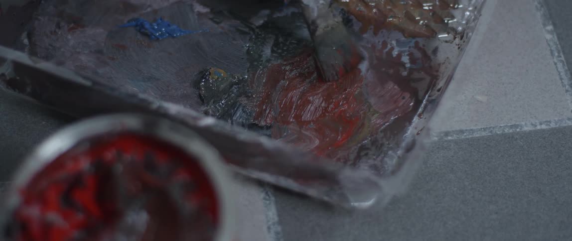 A paintbrush mixes paint on a palette