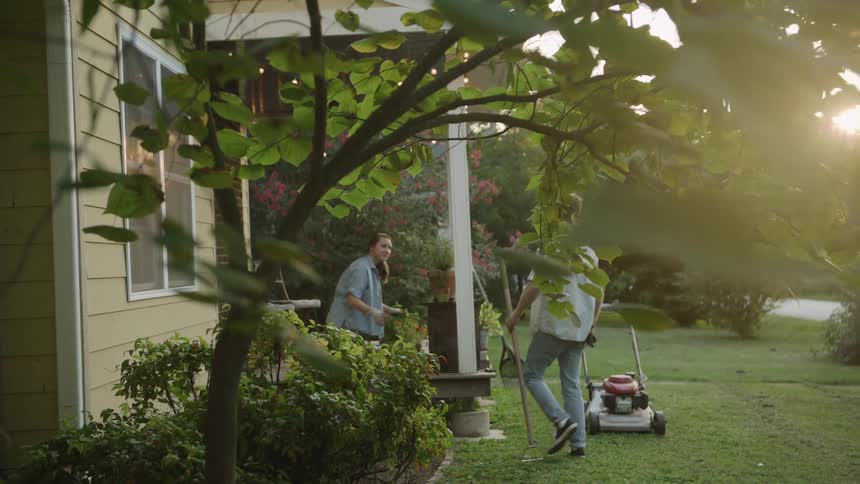 A man and woman do yard work in the front yard