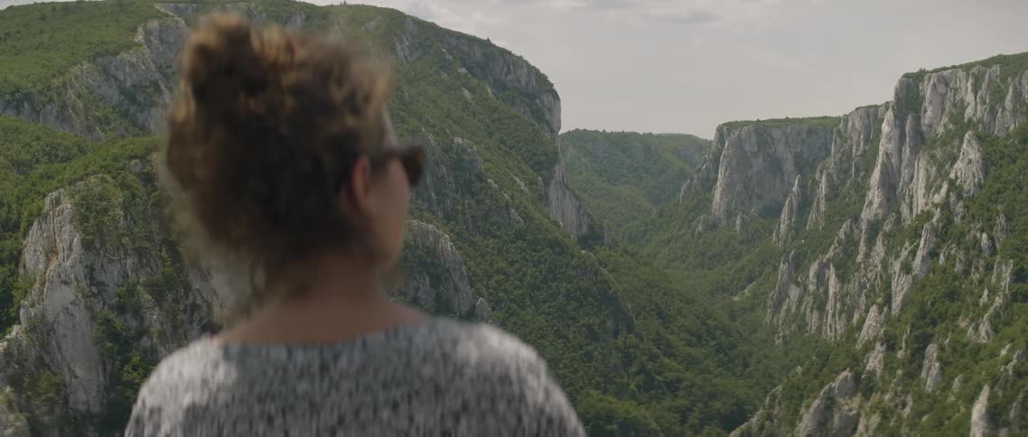 The woman looks out over the mountain range