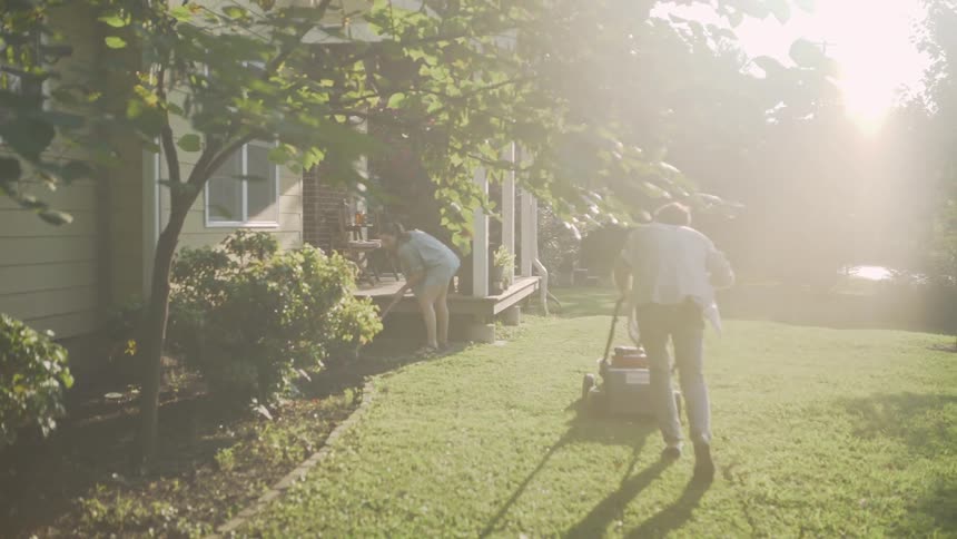 The two people work on mowing the grass and gardening