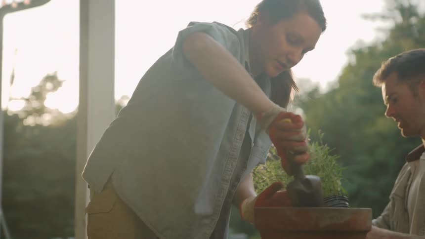 The woman is planting in a pot on her porch