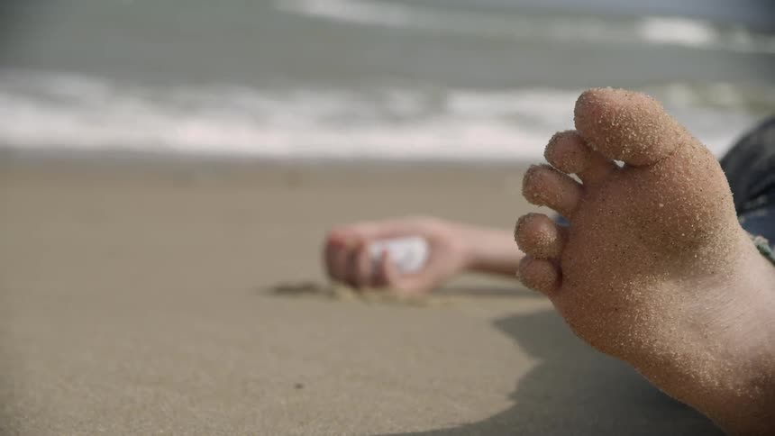 Sun shines down on a person lying on the beach