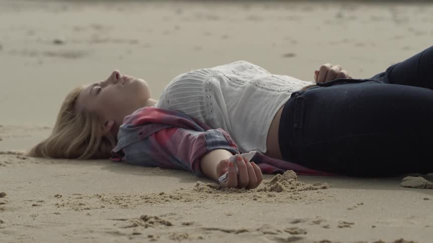 Woman lays on a sandy beach