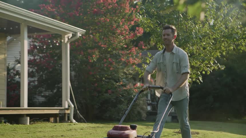 A man mows a front lawn