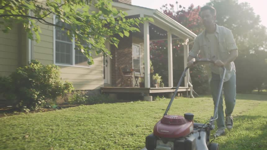 A man mows a lawn on a sunny day
