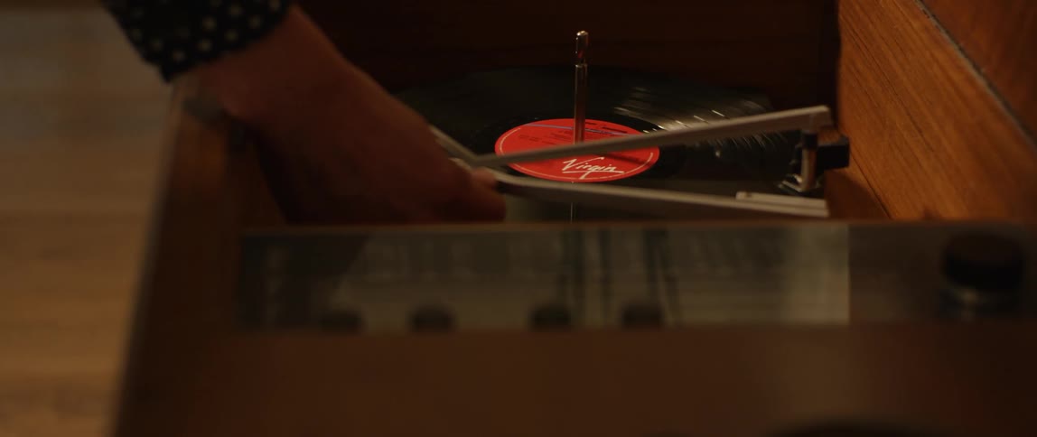 Person starts a record player and the record starts spinning