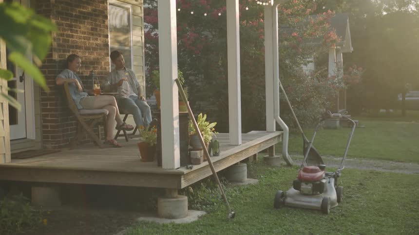 Man and woman sit on the porch and the man waves
