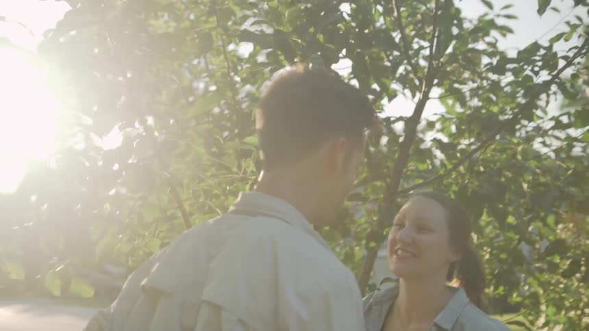 A man and woman kiss next to an apple tree