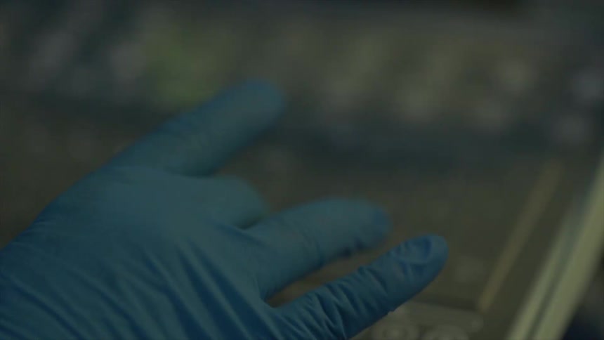 A gloved hand presses keys on a piece of equipment