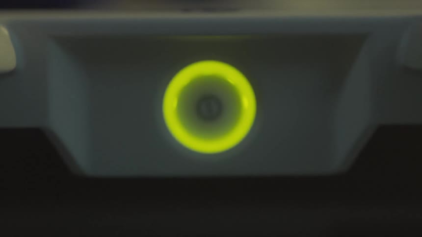 An illuminated green power button slowly comes into focus