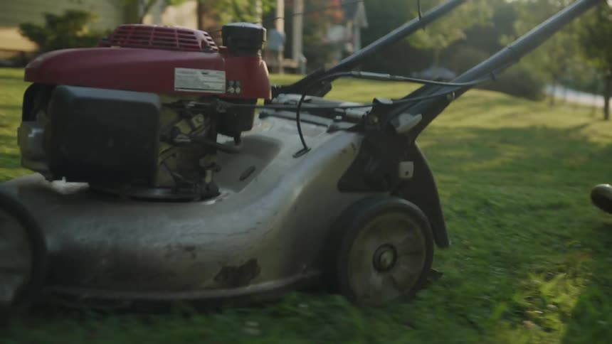 A man mows a lawn on a sunny day