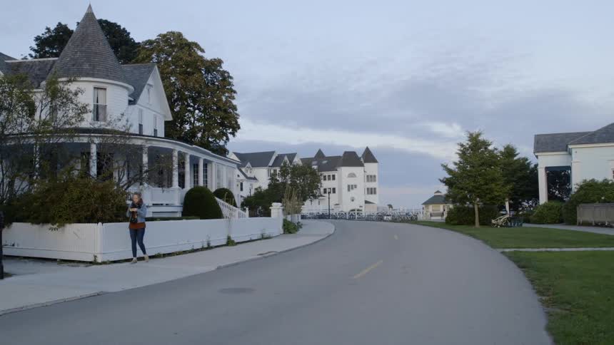 A woman walks on a neighborhood sidewalk