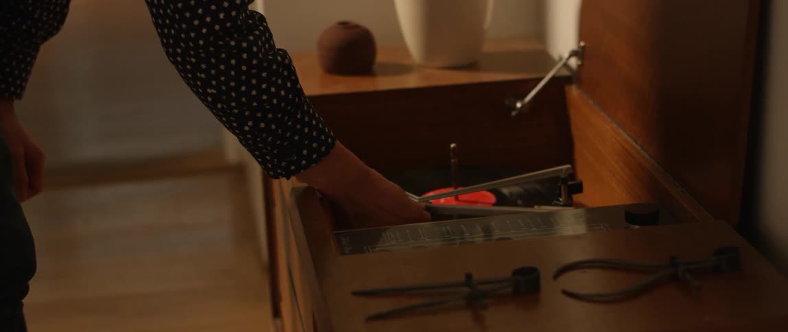 Person turns on a turntable and the record starts spinning