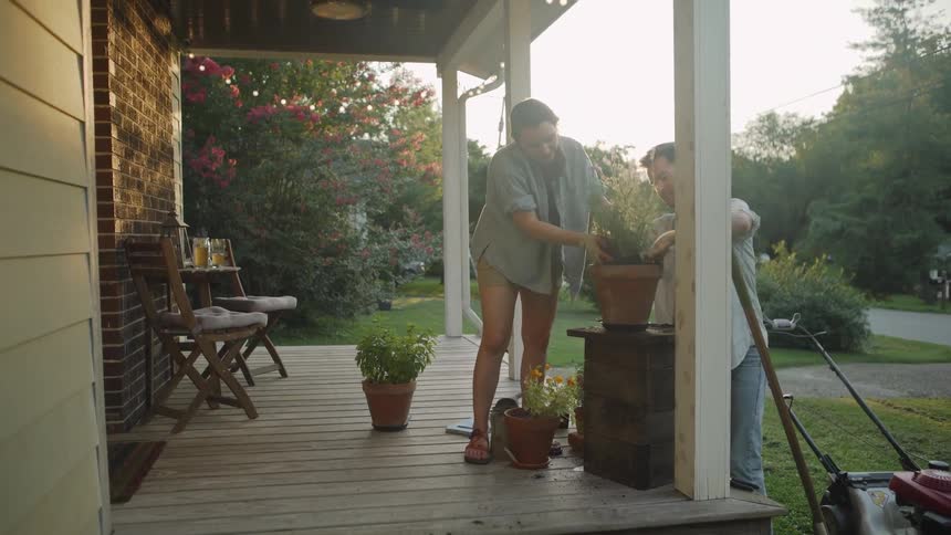 Young Couple Puts Plant into a Pot on Porch