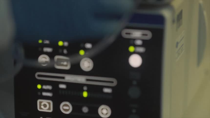 A hand touches some dials on a medical device