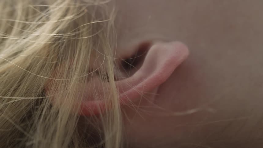 The hair is blowing around the person's ear