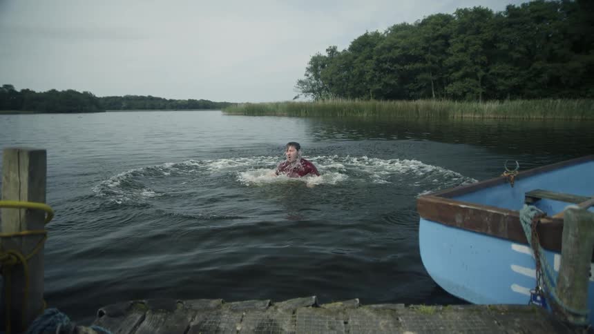 Man splashes into a lake next to a boat