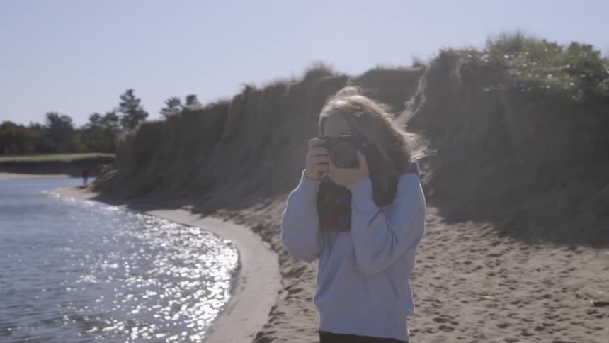 The woman is taking photographs on the beach