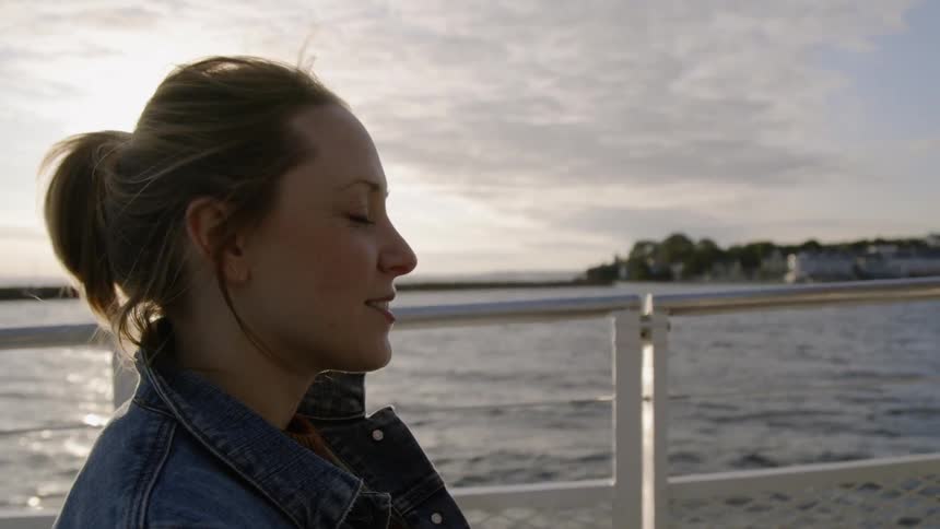 A woman smiles while boating on a lake at sunset