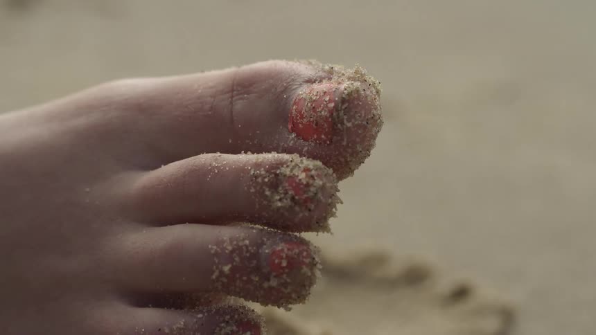 Sand sits on the end of a woman's toes