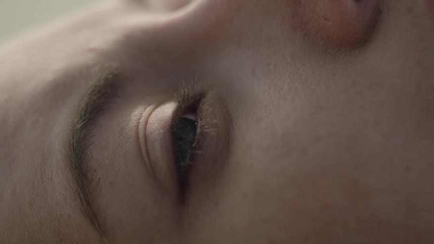 A woman lying down opens her eyes in the sunlight