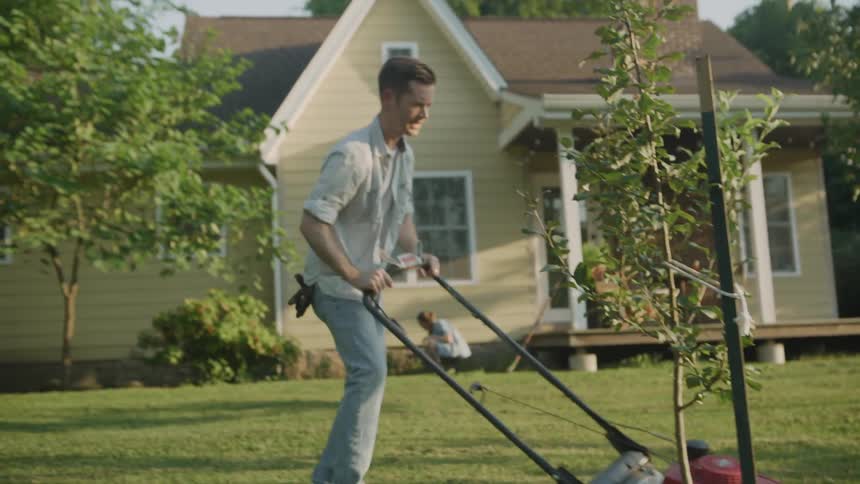 Man mows the front lawn of his house