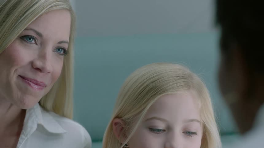 A young girl and her parent talking with another person