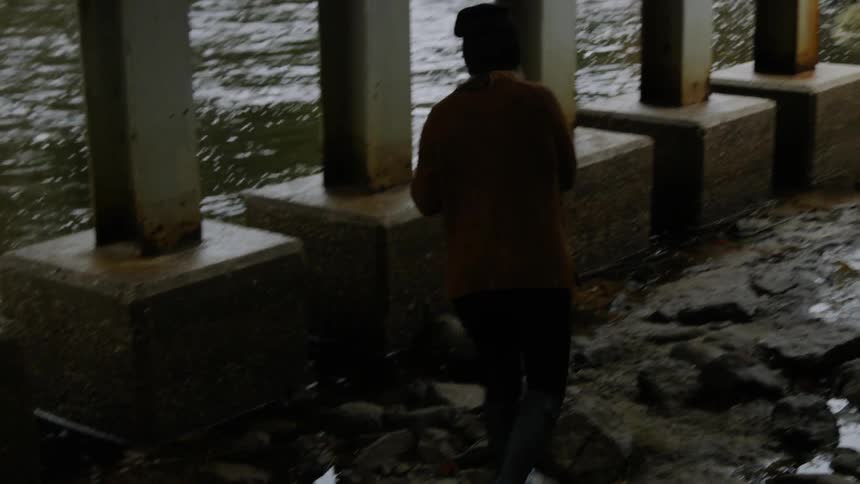 The man walks under the bridge by the stream