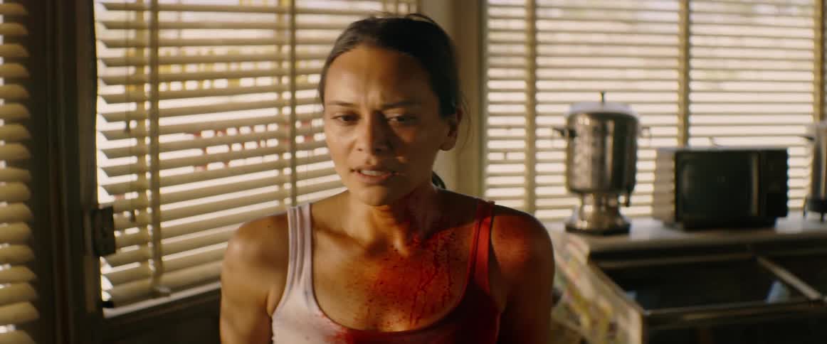 Panicked woman spattered in blood looks down at herself