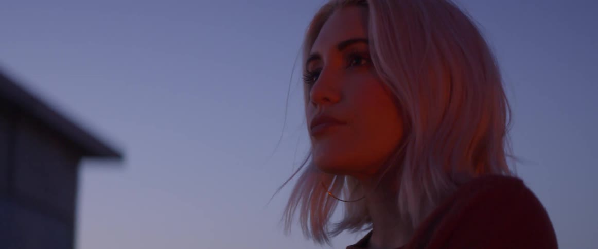 Woman stands outside by firelight at night