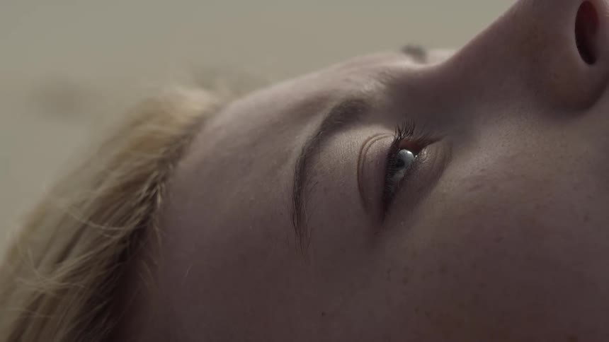 A woman slowly opens her eyes while lying down