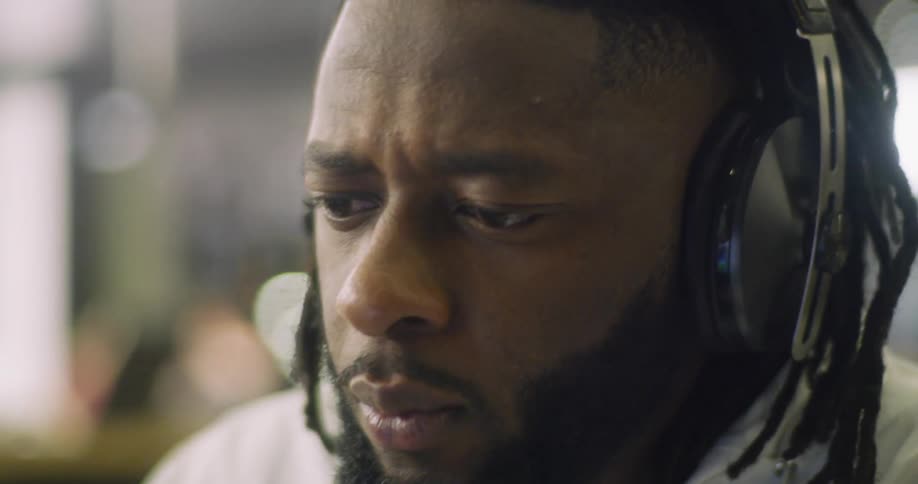 The man is wearing headphones and nodding his head