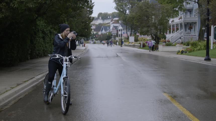 Woman on a bike takes pictures of a city