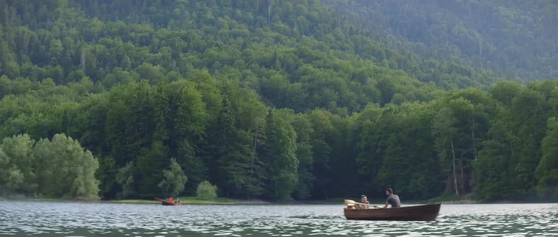 A man rows a boat on a mountain lake
