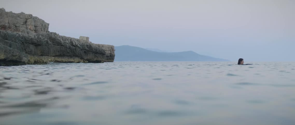 The person floats in the water by the shore