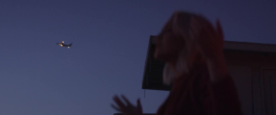 The woman raises her arms and goes into prayer on the beach at dawn