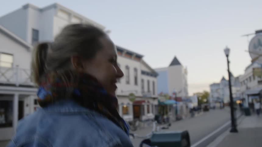 The woman walks down the road smiling on a cloudy day