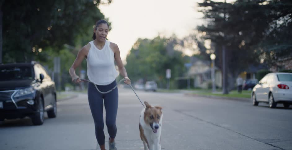 The woman has fun running with her dog down the street