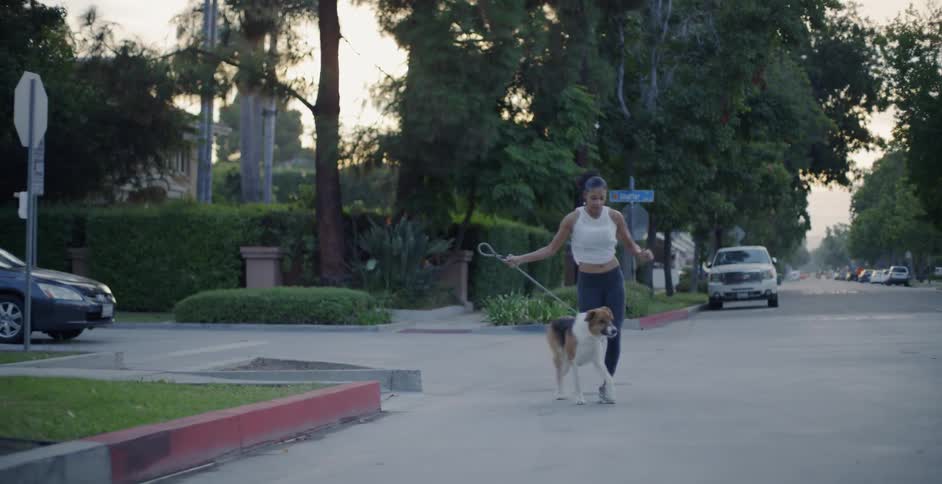 A woman jogs around the corner with her dog