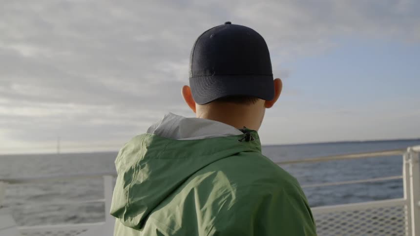 The man watches the water from the boat